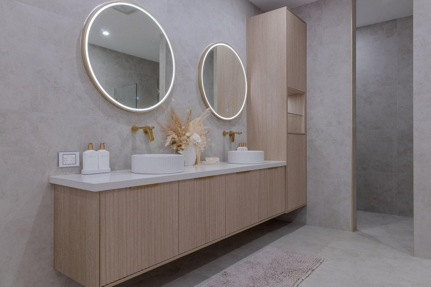 Custom timber bathroom vanity with a stone top and round mirrors